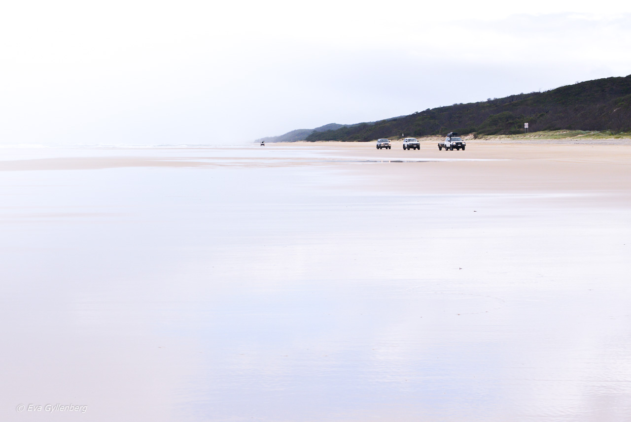 Tre bilar på en strand i Australien