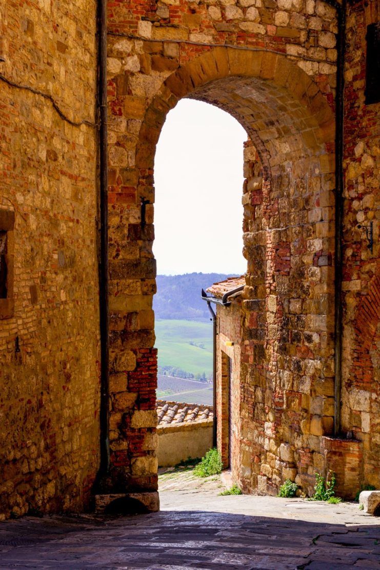 En mur med en port med utsikt över vingårdar i Toscana