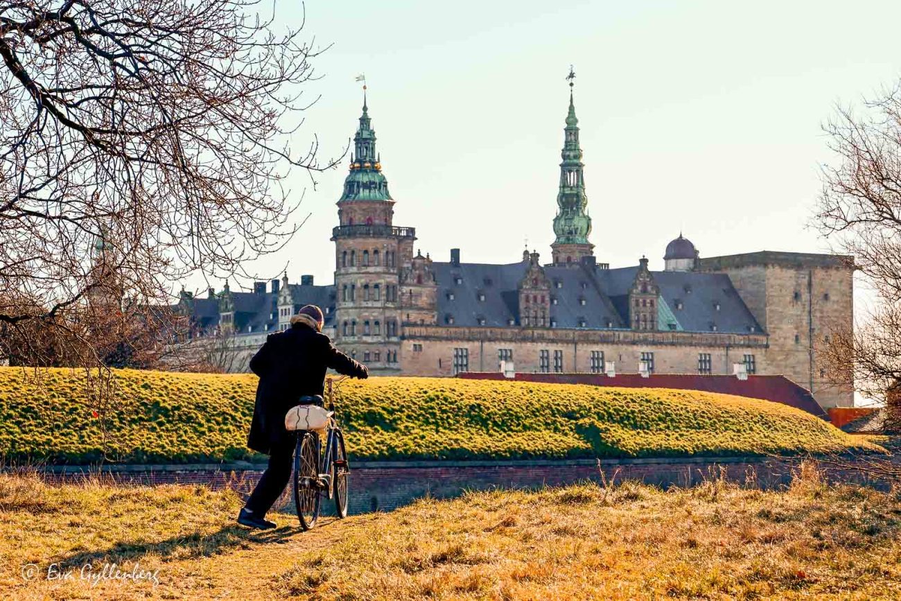 Cyklist hoppar på sin cykel utanför Kronborg slott med sina torn