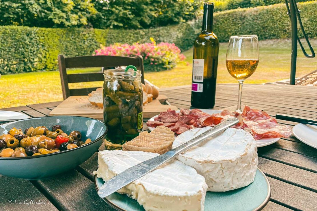 Ostar, charkuterier, cornichoner och oliver på ett bord utomhus i Frankrike