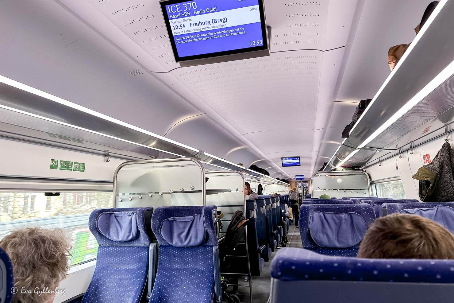 Tågvagn i Tyskland med blå säten och information på TV