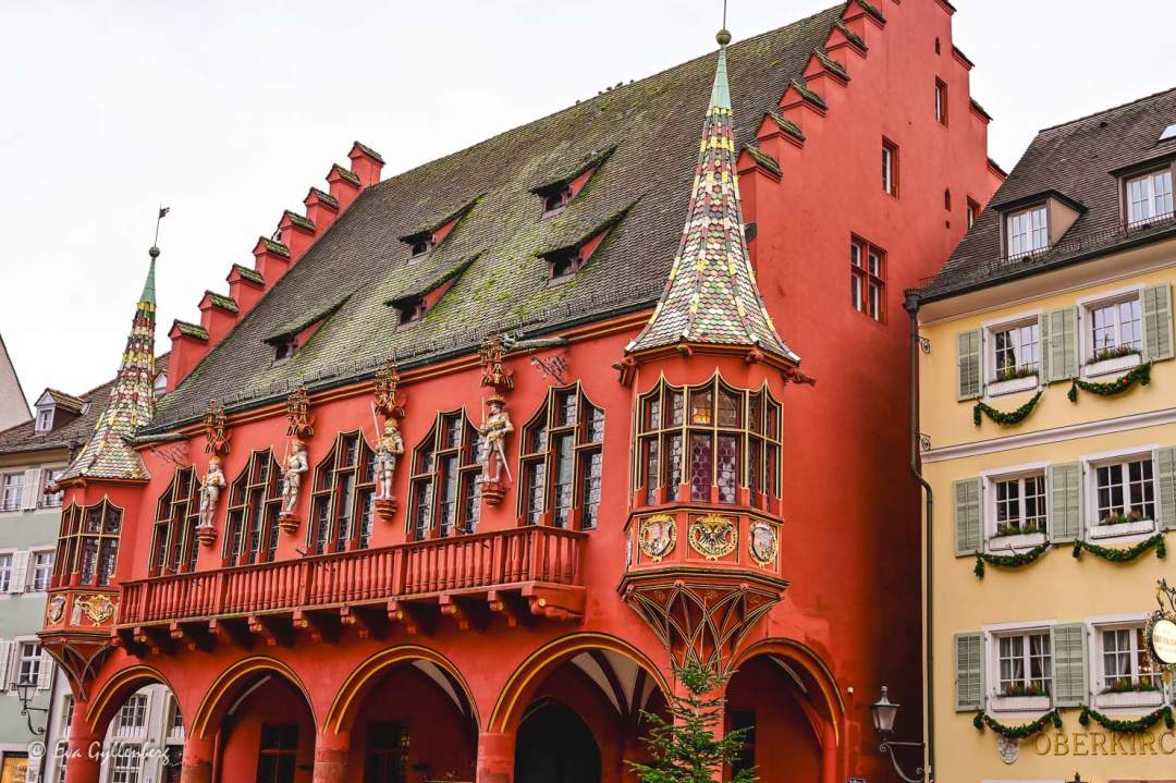 En vacker röd byggnad på Münsterplatz med färgat kakeltak med torn