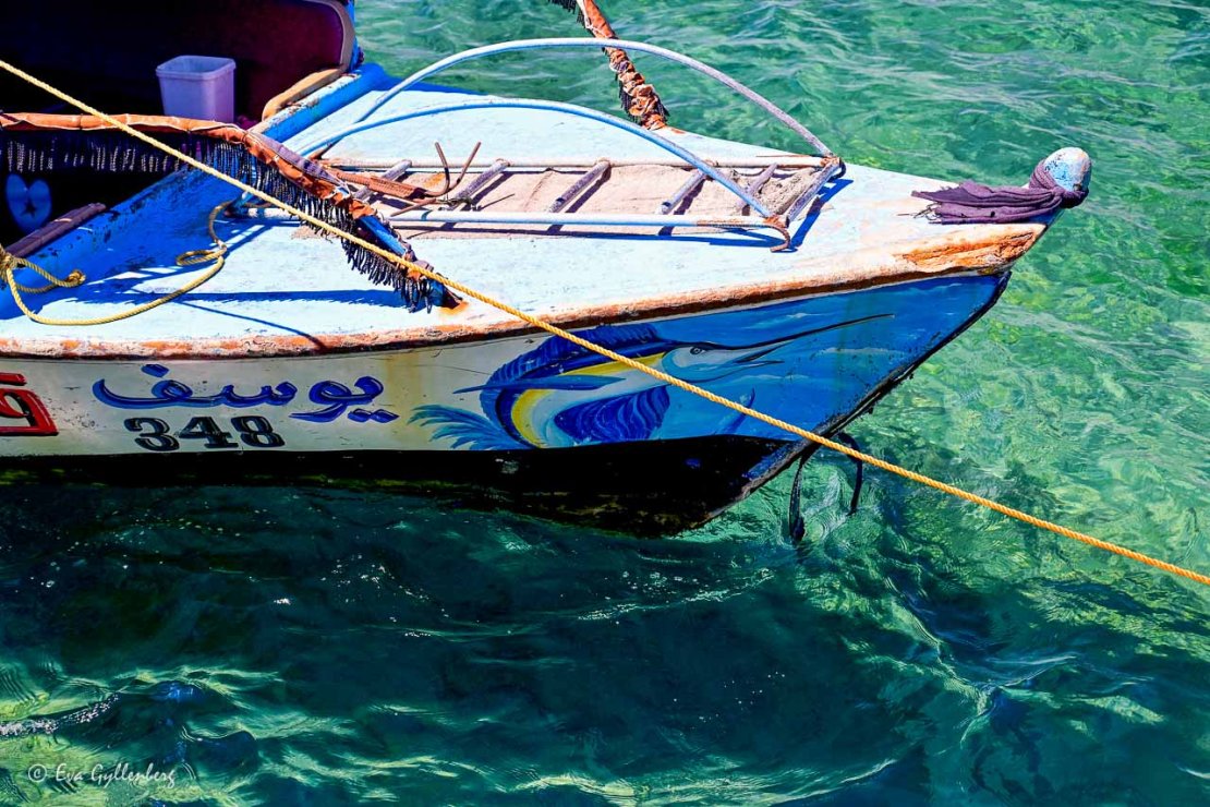 Klart och turkost vatten under en båt i Aqaba