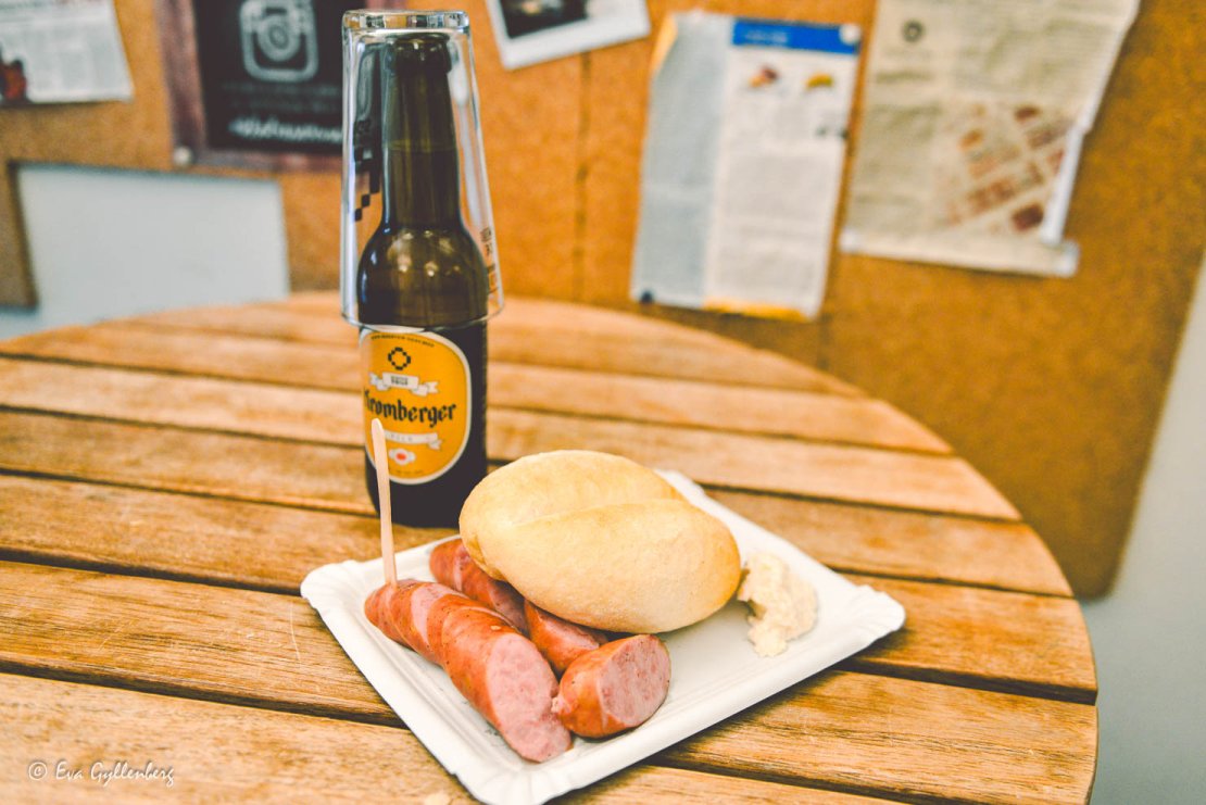 Carniola-korv med bröd och senap på ett bord med en öl