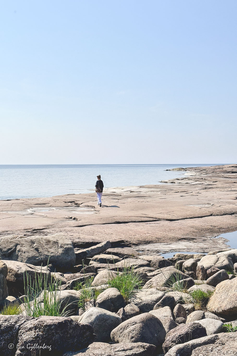 flicka går på klipphäll vid havet