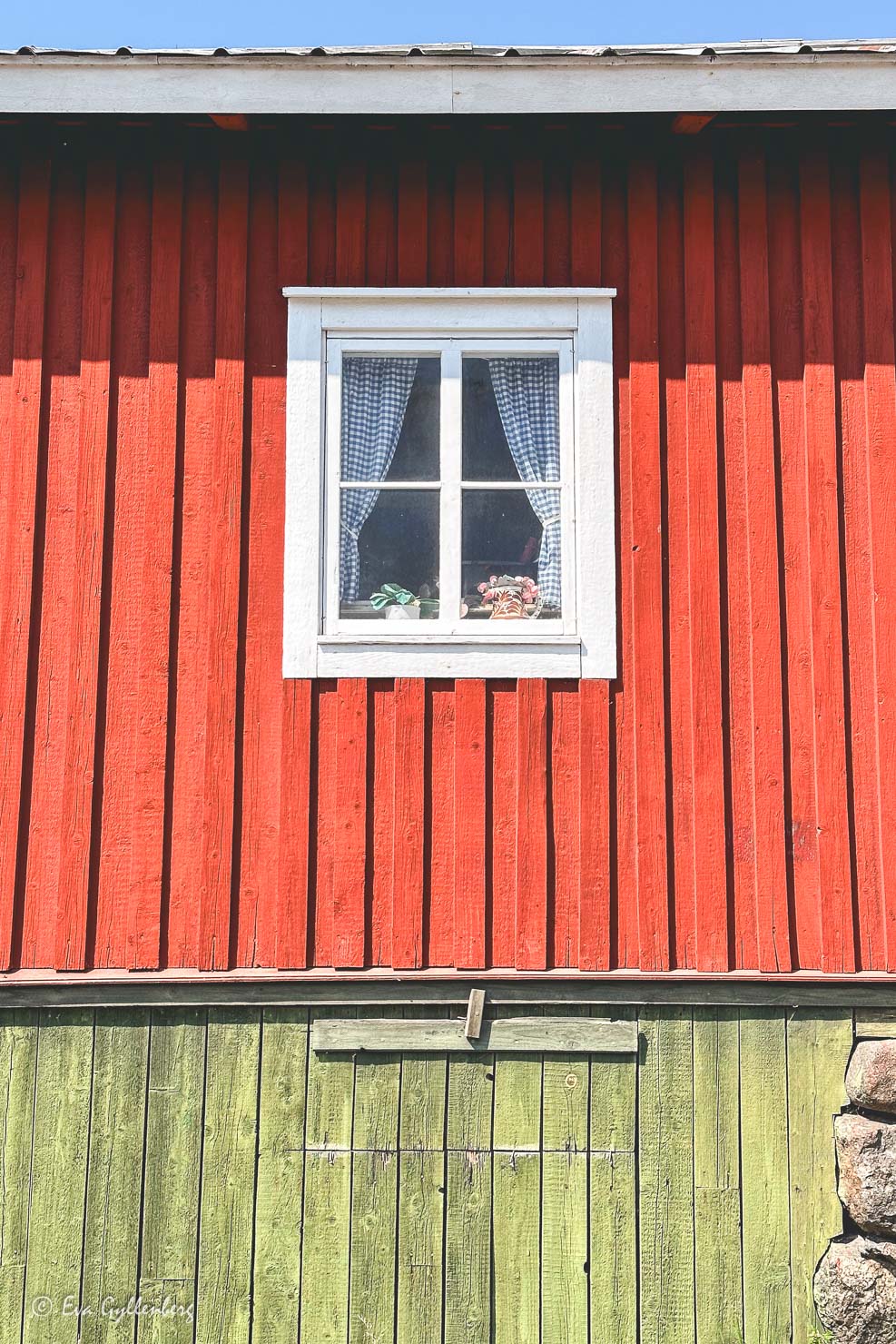 rött trähus med fönster med blårutiga gardiner