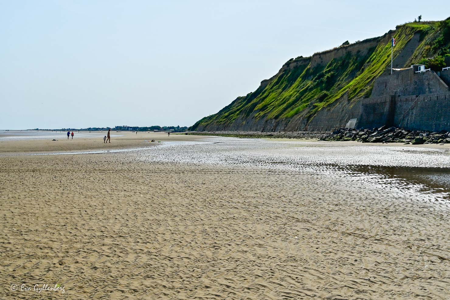 Klippor och breda gyllende sandstrand en solig dag