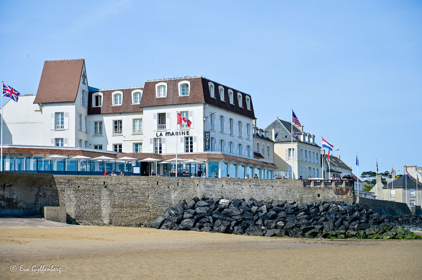 Vitt hus med restaurang och flaggor vid en strand