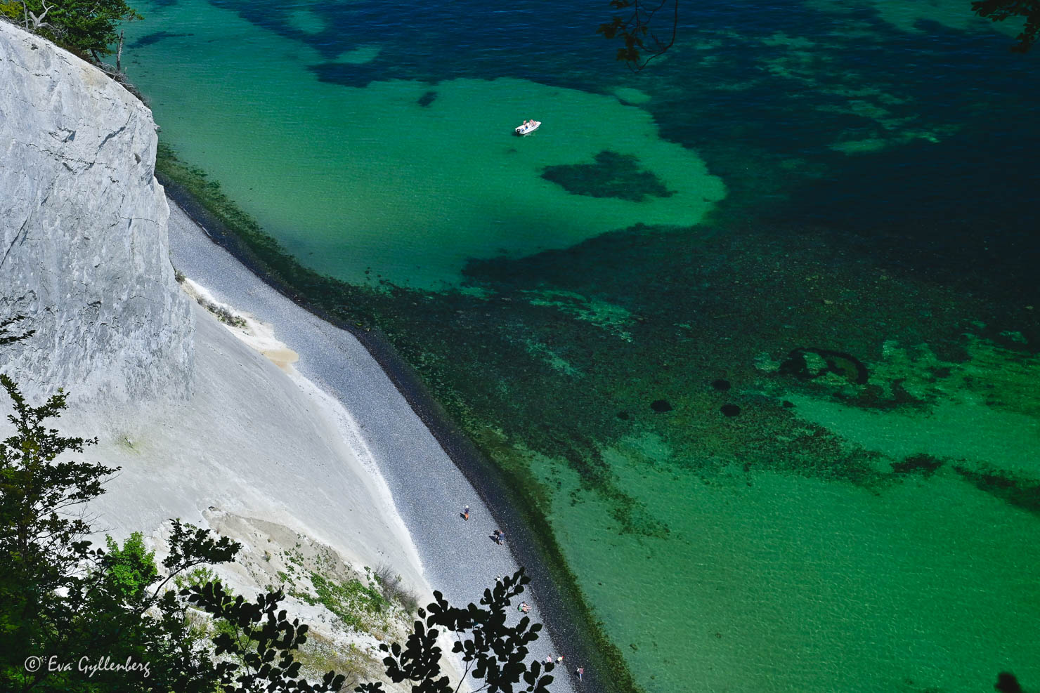 en liten båt ligger vi en strand med klargrönt vatten