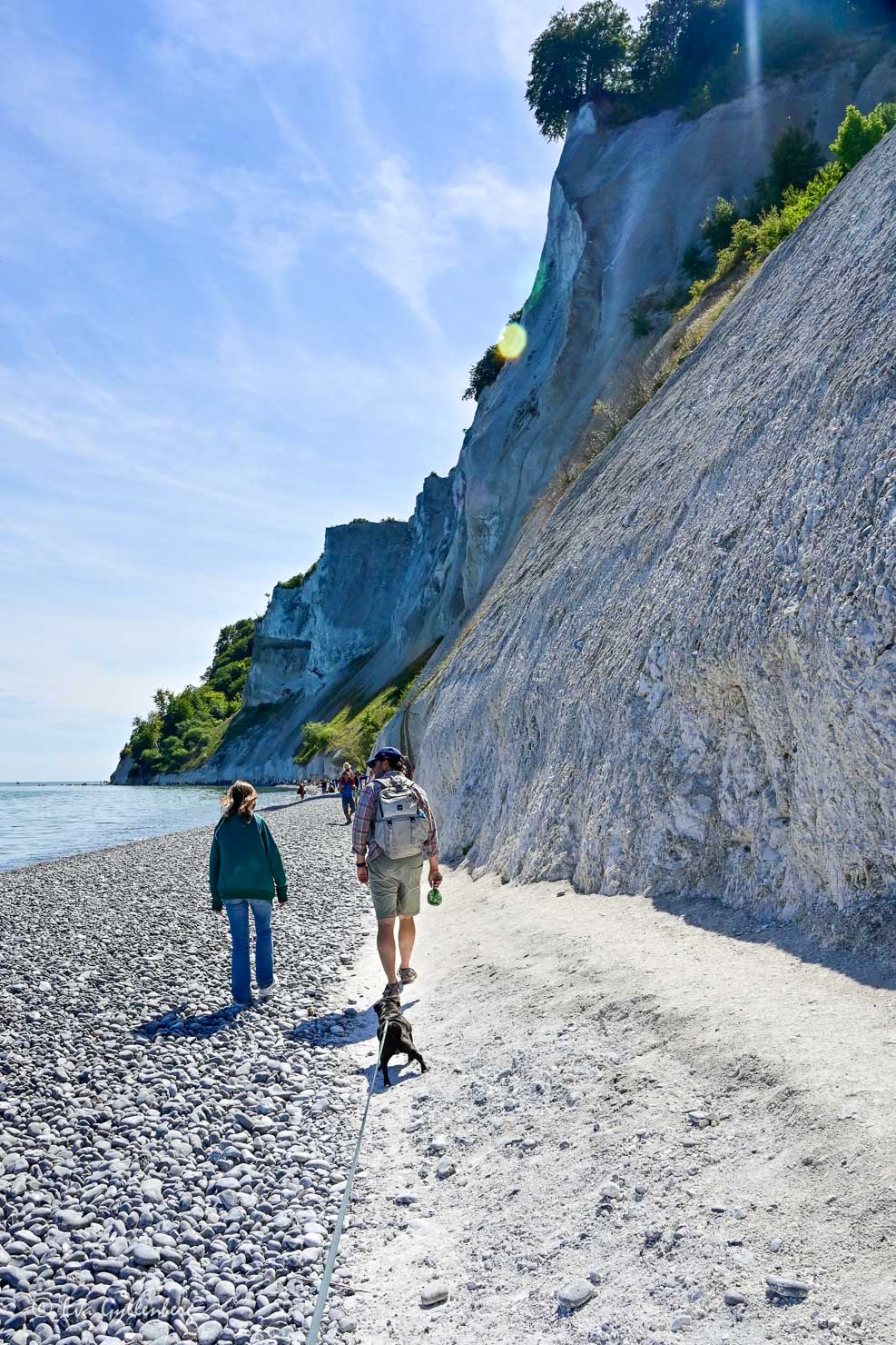 två människor som går längs en strand med branta klippor på en sida