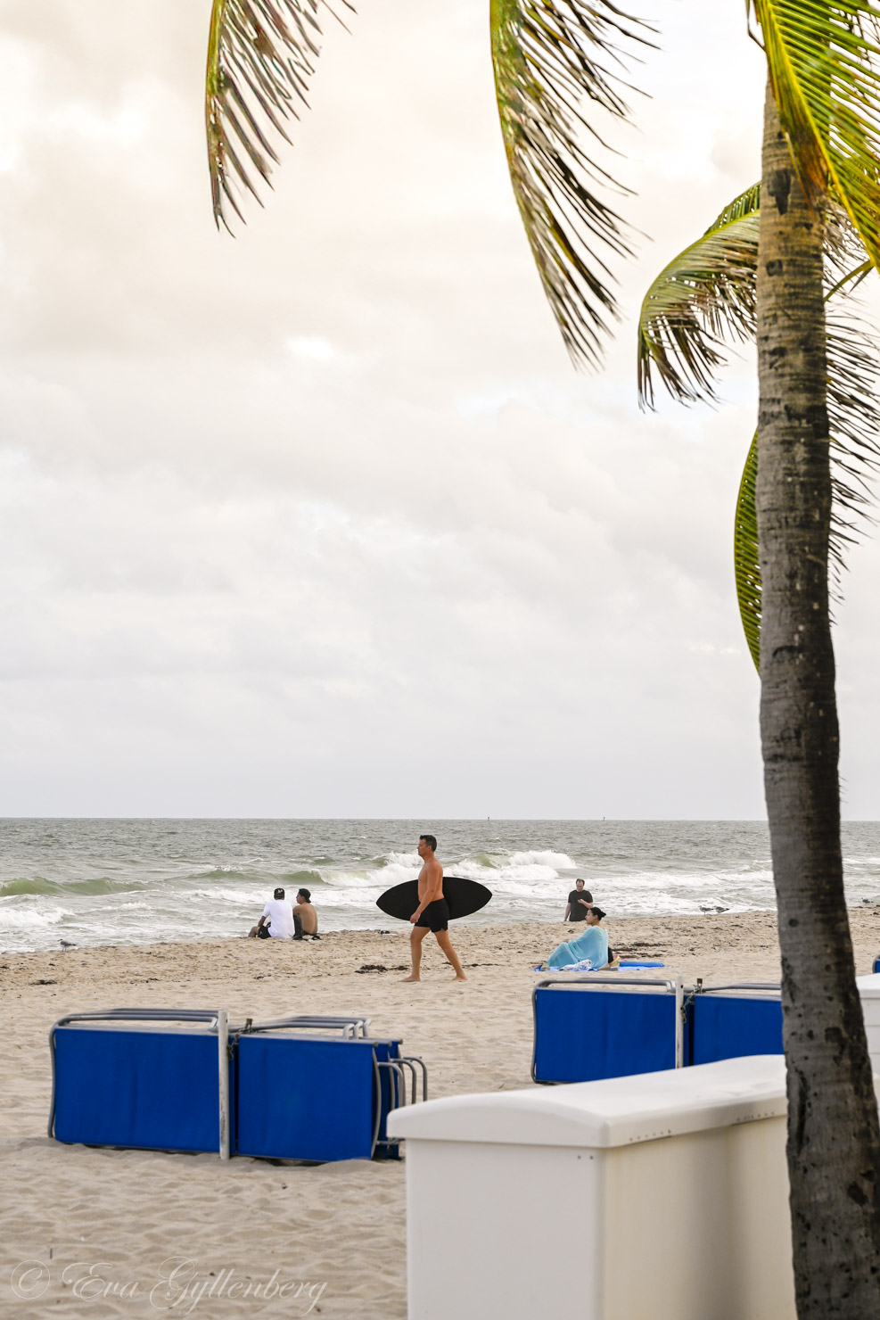 en man går med surfbräda på en palmklädd strand