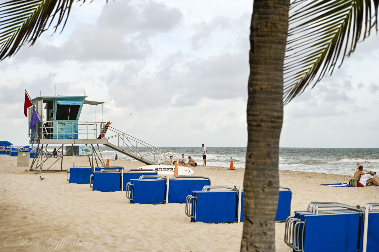 blå solstolar ligger på en strand vid ett livräddartorn