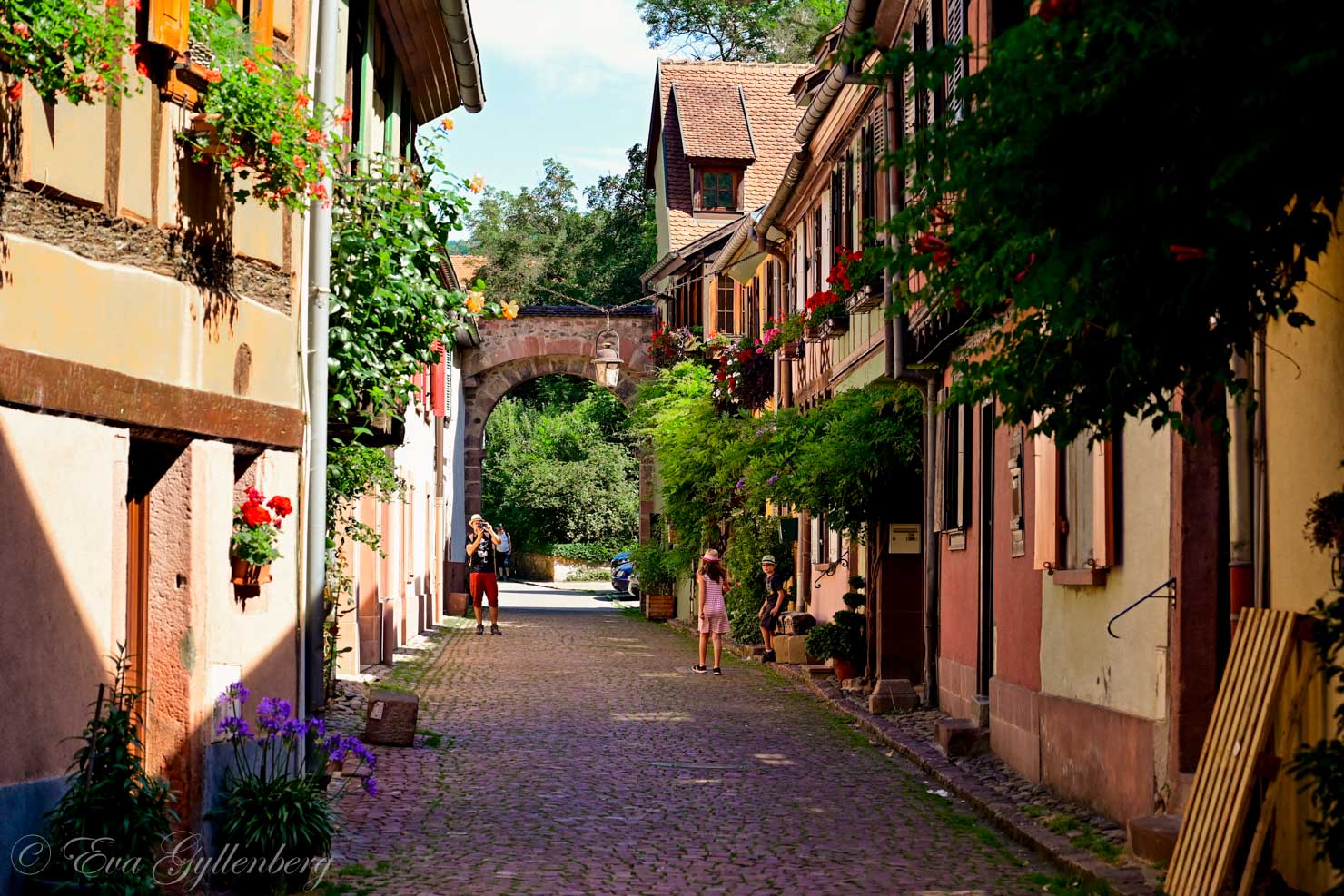 Liten kullerstensgata med turister i Alsace